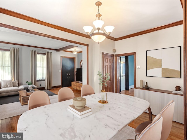 dining space with light hardwood / wood-style floors, crown molding, and a chandelier