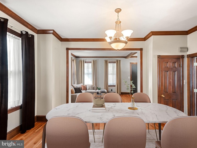 dining area featuring a chandelier, light hardwood / wood-style flooring, and crown molding