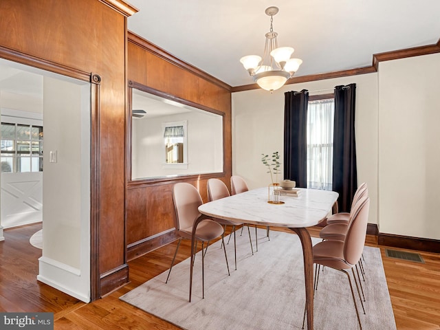 dining space featuring hardwood / wood-style flooring, ornamental molding, and a notable chandelier