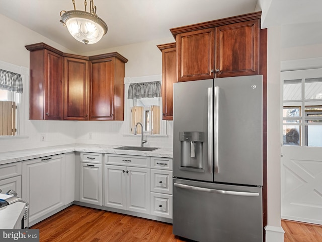 kitchen with stainless steel fridge, sink, a healthy amount of sunlight, and light hardwood / wood-style flooring