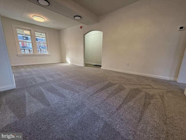 carpeted empty room featuring beamed ceiling