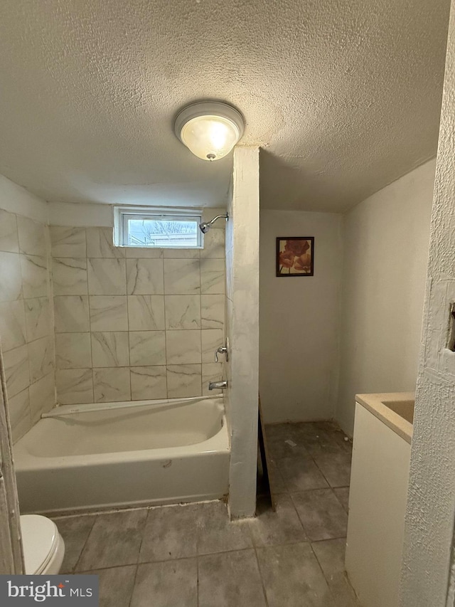 full bathroom featuring vanity, a textured ceiling, tiled shower / bath combo, and toilet