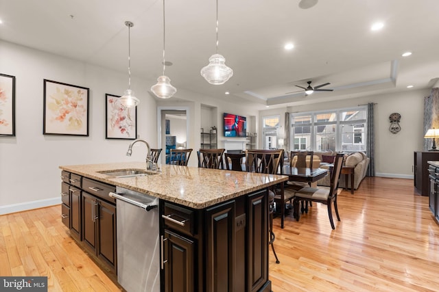 kitchen featuring dishwasher, a raised ceiling, a breakfast bar area, and sink