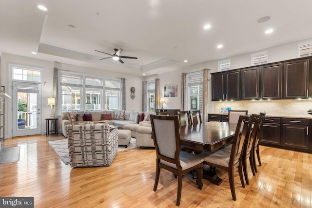 dining room featuring a tray ceiling, ceiling fan, and light hardwood / wood-style floors