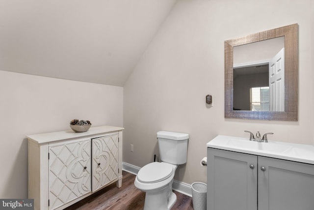 bathroom with vanity, toilet, wood-type flooring, and vaulted ceiling