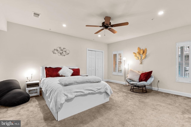 bedroom featuring ceiling fan, light carpet, and a closet