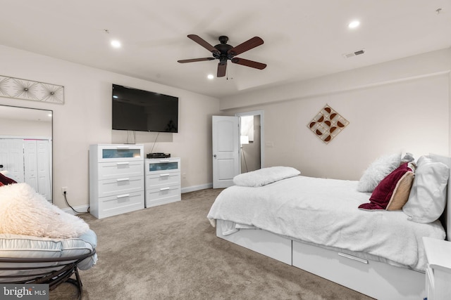 bedroom with ceiling fan, light carpet, and a closet