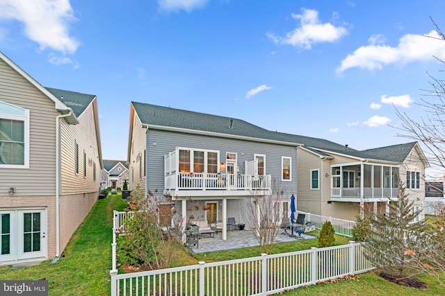 back of property with a yard, a balcony, and a patio area