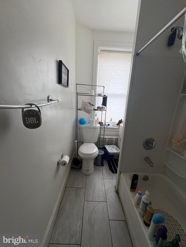 bathroom with baseboards, shower / bathing tub combination, and toilet