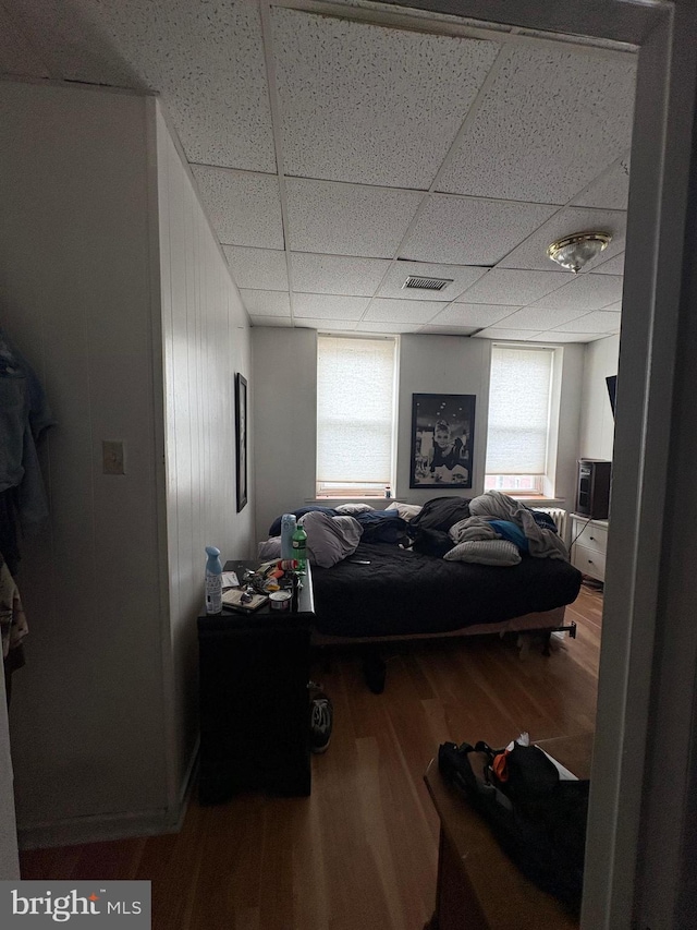 bedroom featuring a drop ceiling, wood finished floors, and visible vents