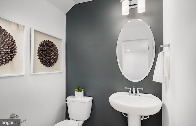 bathroom with toilet, sink, and vaulted ceiling