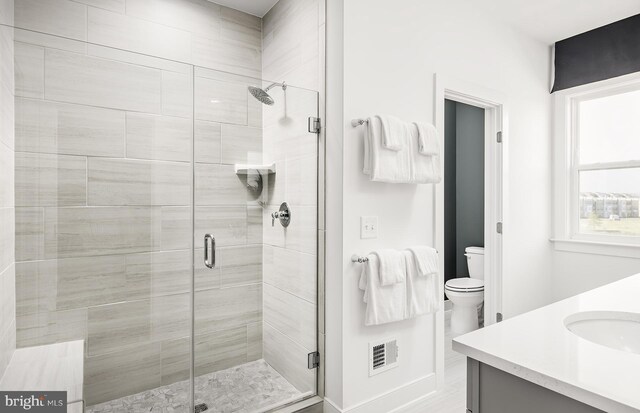 bathroom with vanity, toilet, and a shower with shower door