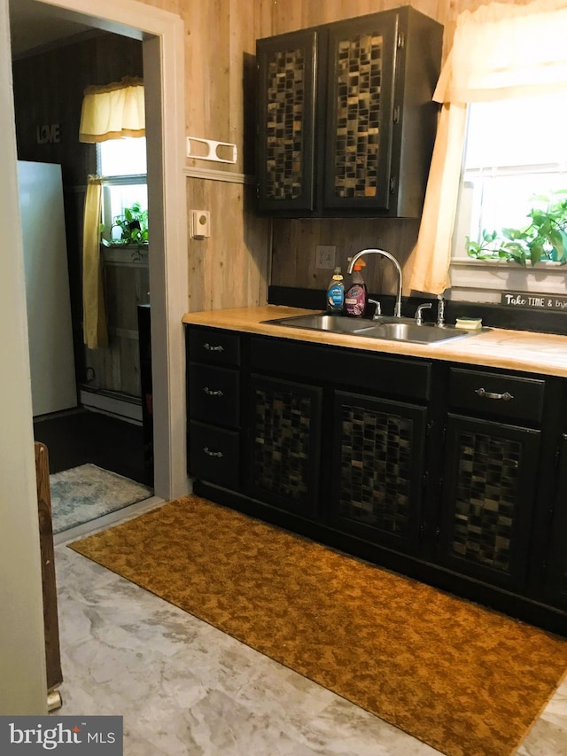 bar with baseboard heating, wood walls, and sink