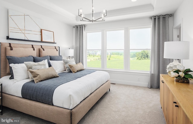 bedroom featuring light carpet, a raised ceiling, and a notable chandelier