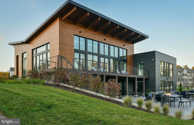 back of house featuring a patio, a balcony, and a lawn