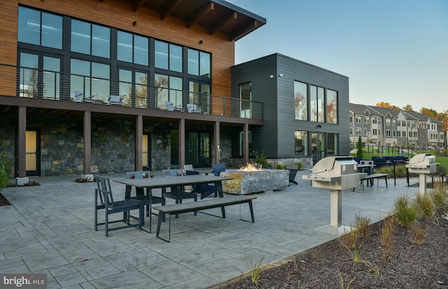 rear view of house with a fire pit, a balcony, and a patio