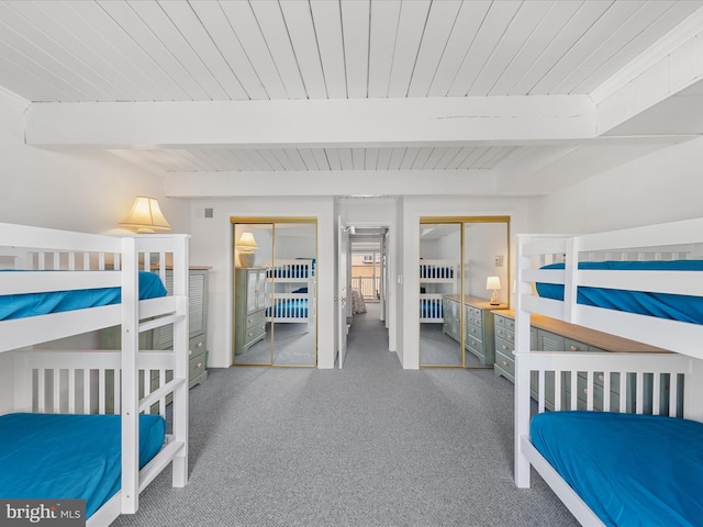 unfurnished bedroom featuring multiple closets, carpet, beam ceiling, and wood ceiling