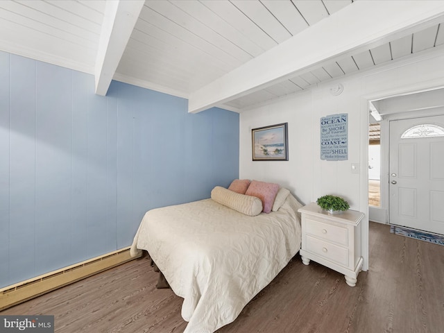 bedroom featuring a baseboard heating unit, wood finished floors, and beam ceiling