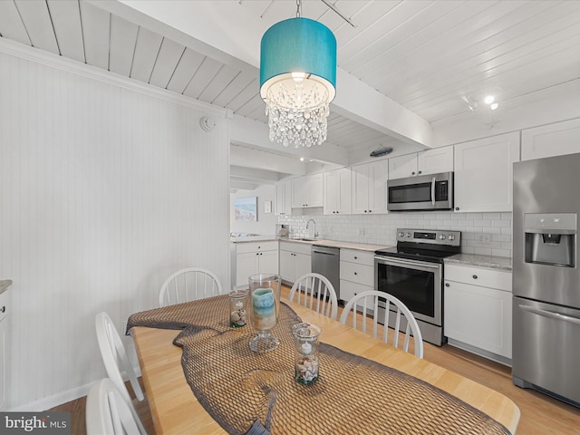 dining space with a chandelier, beam ceiling, wooden ceiling, and light wood finished floors