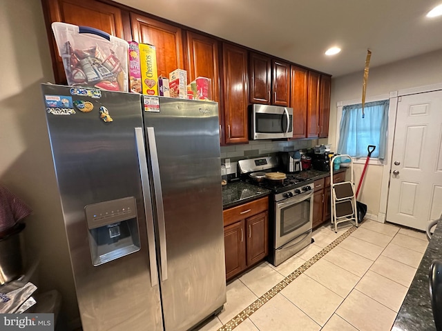 kitchen with dark stone countertops, light tile patterned floors, tasteful backsplash, and appliances with stainless steel finishes