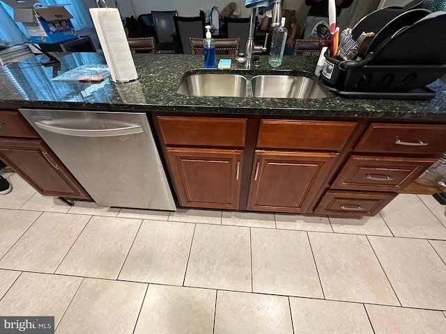 kitchen featuring stainless steel dishwasher, light tile patterned floors, sink, and dark stone countertops