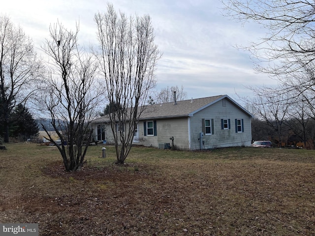 rear view of house featuring central AC unit and a yard