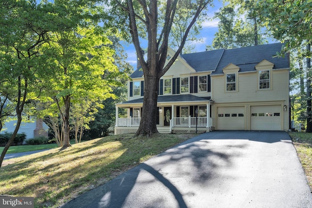 view of front of home with a garage, a porch, and a front yard