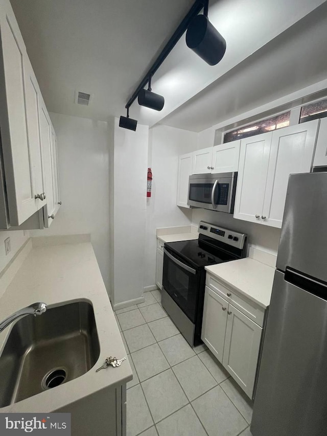 kitchen featuring white cabinets, stainless steel appliances, light tile patterned flooring, and sink