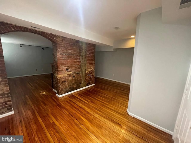 empty room featuring wood-type flooring and brick wall