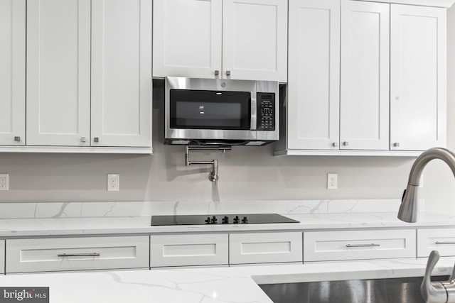 kitchen with white cabinetry, light stone countertops, and black electric cooktop