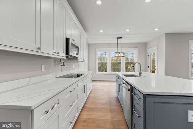 kitchen with sink, hanging light fixtures, a center island with sink, appliances with stainless steel finishes, and white cabinets