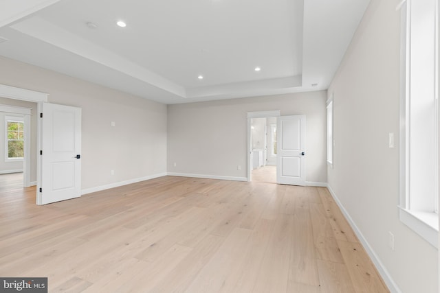 unfurnished room with a tray ceiling and light hardwood / wood-style floors