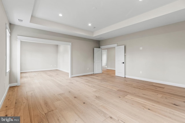 unfurnished bedroom with light hardwood / wood-style floors and a raised ceiling