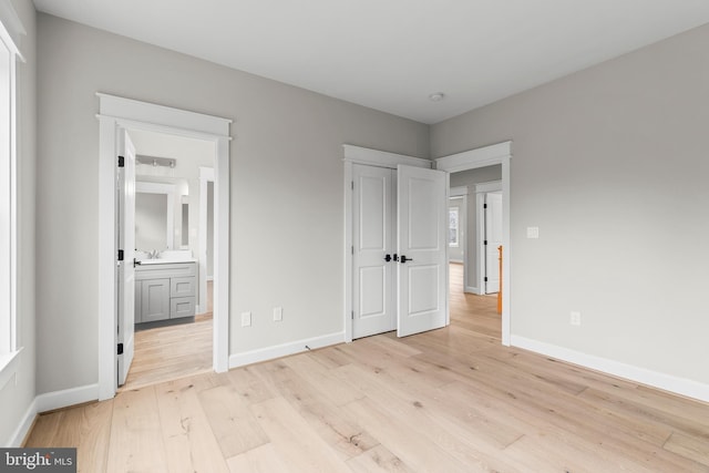 unfurnished bedroom featuring sink, ensuite bath, and light hardwood / wood-style flooring