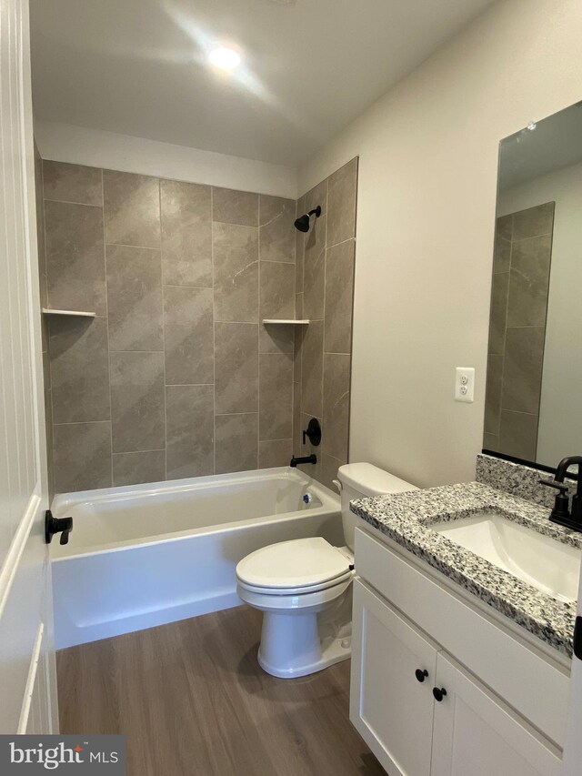 full bathroom with hardwood / wood-style flooring, vanity, toilet, and tiled shower / bath