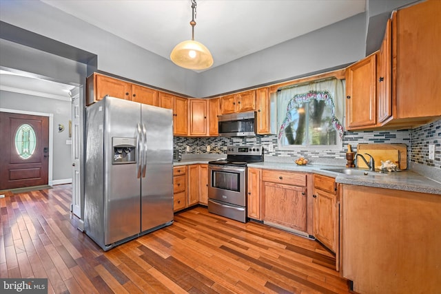 kitchen with decorative light fixtures, sink, wood-type flooring, and appliances with stainless steel finishes