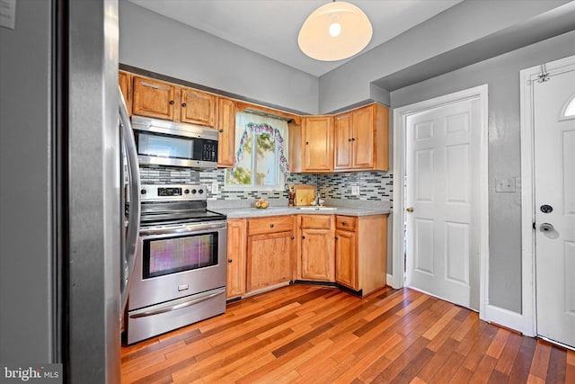 kitchen with sink, light hardwood / wood-style flooring, appliances with stainless steel finishes, and tasteful backsplash