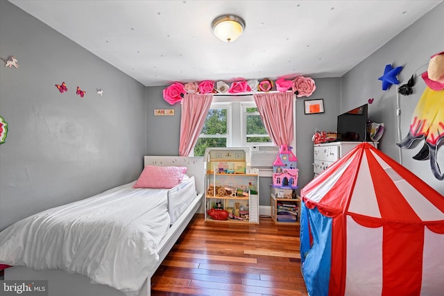 bedroom with cooling unit and dark hardwood / wood-style floors