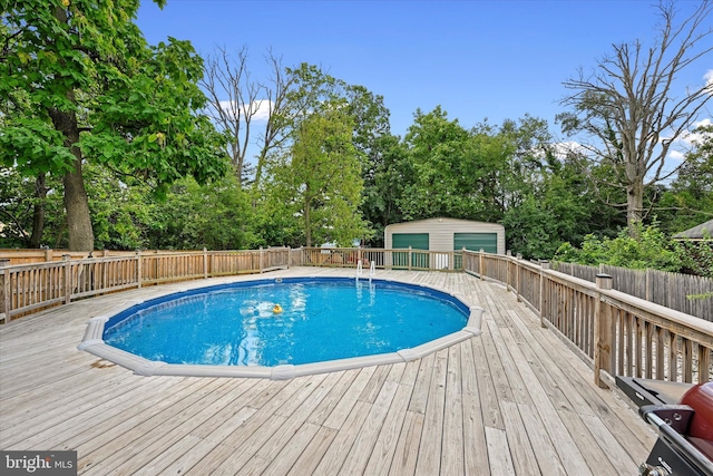 view of pool with an outdoor structure, a wooden deck, and a garage