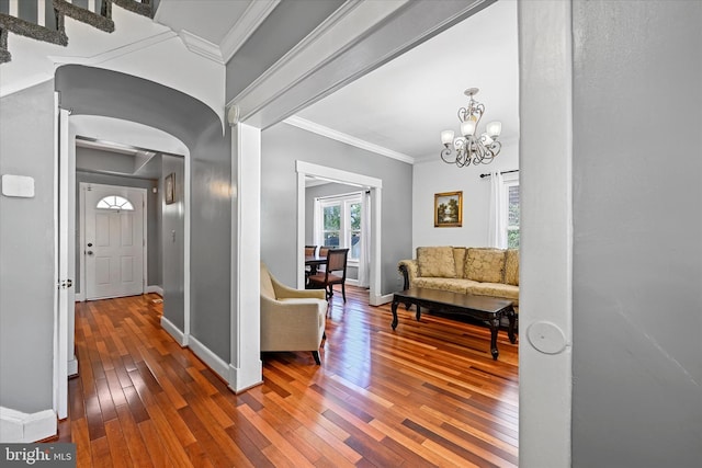 hall with hardwood / wood-style flooring, ornamental molding, and a notable chandelier