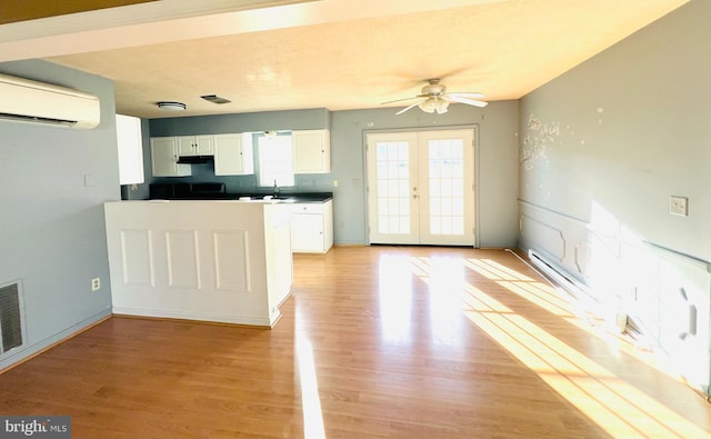 kitchen featuring sink, french doors, light hardwood / wood-style flooring, a wall mounted AC, and white cabinets