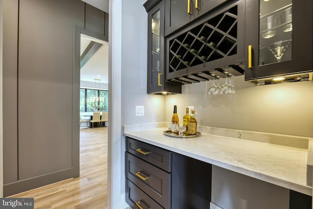 bar with light stone countertops and light wood-type flooring