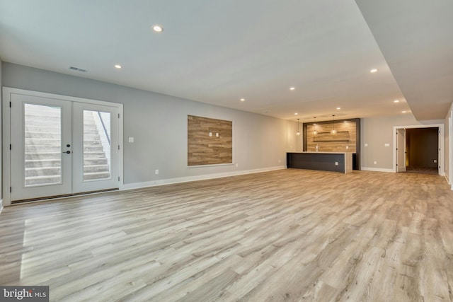 unfurnished living room with french doors and light hardwood / wood-style floors