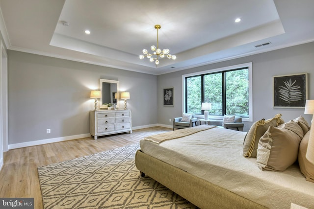 bedroom with hardwood / wood-style floors, a chandelier, crown molding, and a tray ceiling