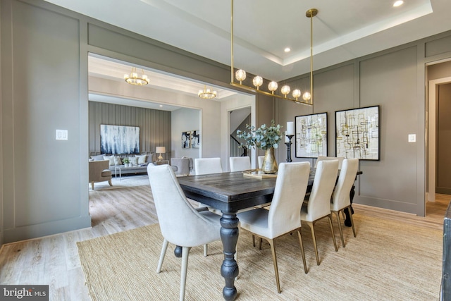 dining area with a tray ceiling and light hardwood / wood-style floors