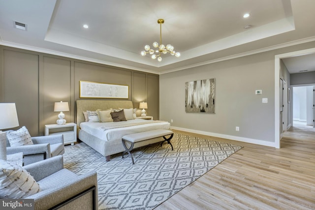 bedroom featuring an inviting chandelier, ornamental molding, light hardwood / wood-style flooring, and a tray ceiling