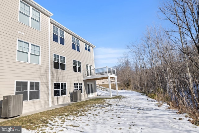 snow covered back of property featuring central air condition unit