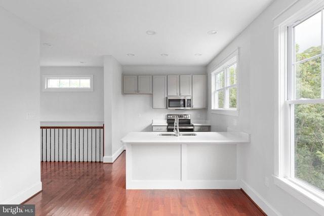 kitchen with kitchen peninsula, stainless steel appliances, gray cabinetry, and sink