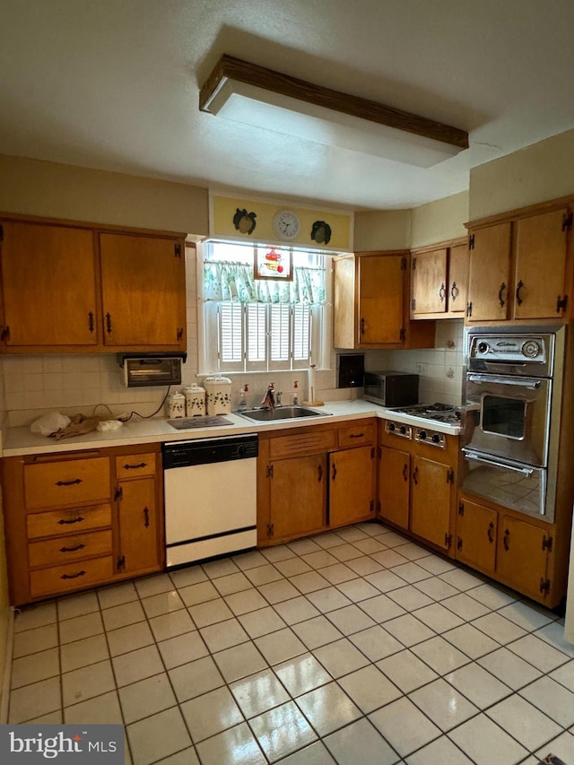 kitchen with backsplash, sink, dishwasher, black oven, and light tile patterned flooring