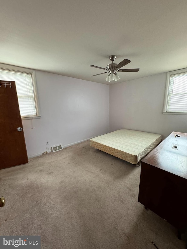 unfurnished bedroom featuring multiple windows, ceiling fan, and carpet